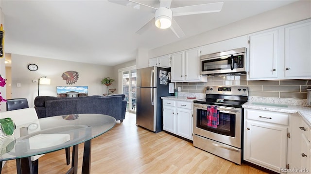 kitchen featuring white cabinets, decorative backsplash, stainless steel appliances, and light hardwood / wood-style flooring