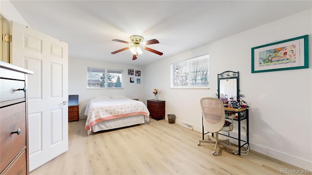 bedroom featuring ceiling fan, light hardwood / wood-style flooring, and multiple windows