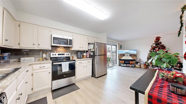 kitchen featuring backsplash, light hardwood / wood-style flooring, white cabinets, and stainless steel appliances