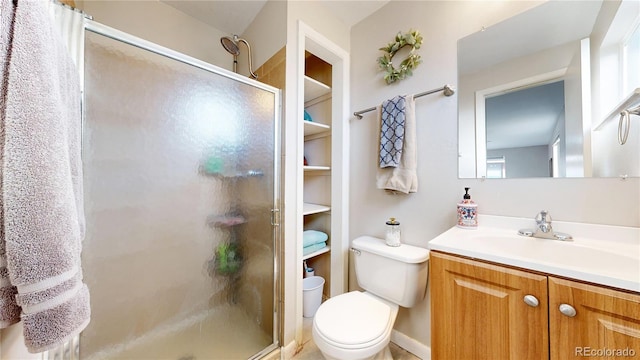 bathroom featuring a shower with door, vanity, and toilet