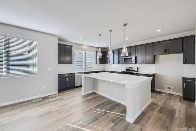 kitchen featuring a wealth of natural light, stainless steel appliances, sink, pendant lighting, and a kitchen island