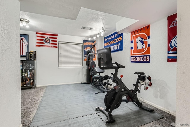 exercise room with track lighting and a textured ceiling