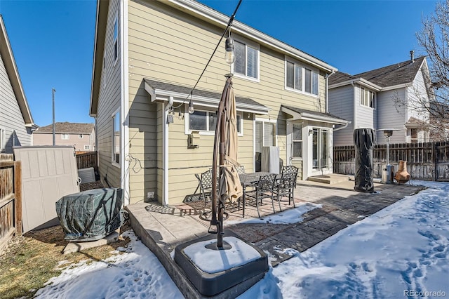 snow covered house featuring a patio area