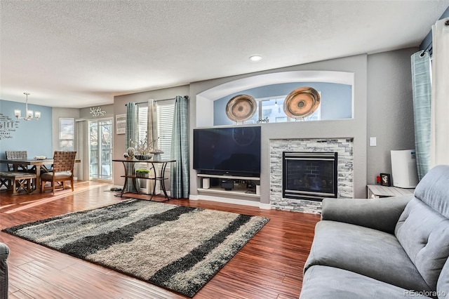 living room featuring a fireplace, a textured ceiling, wood-type flooring, and a chandelier