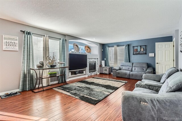 living room featuring a textured ceiling, a fireplace, and wood-type flooring