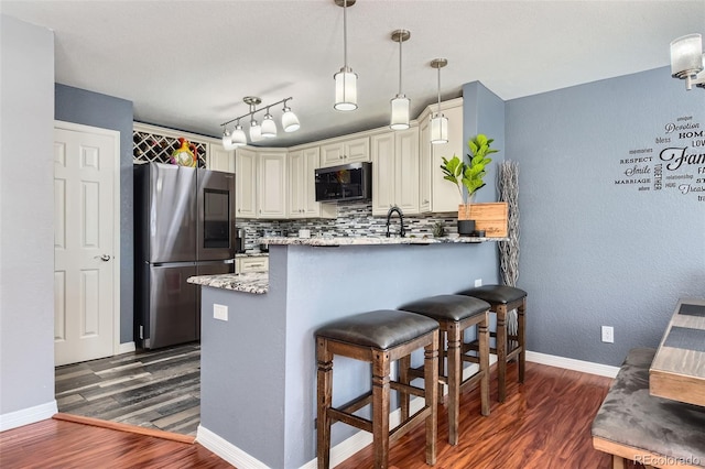 kitchen featuring stainless steel refrigerator, dark hardwood / wood-style floors, decorative backsplash, decorative light fixtures, and kitchen peninsula