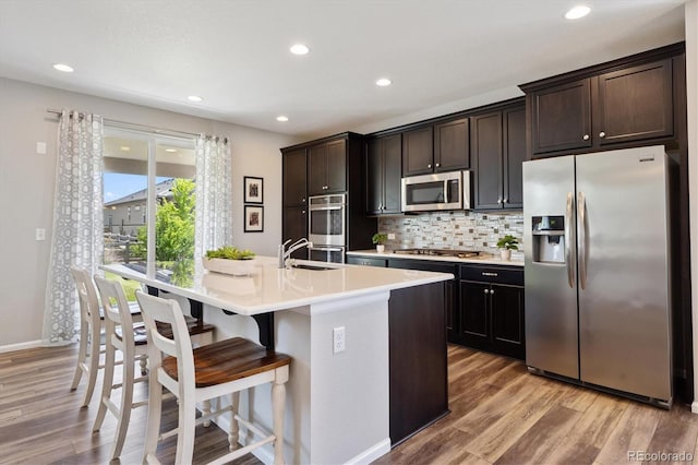 16268 Mount Silverheels Way, Broomfield, CO 80023 - kitchen with appliances with stainless steel finishes, light wood finished floors, tasteful backsplash, a breakfast bar, and recessed lighting