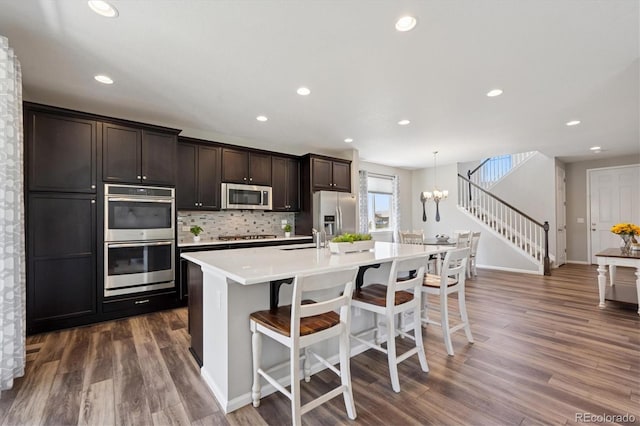 16268 Mount Silverheels Way, Broomfield, CO 80023 - kitchen featuring stainless steel appliances, an island with sink, light countertops, dark brown cabinets, and dark wood finished floors