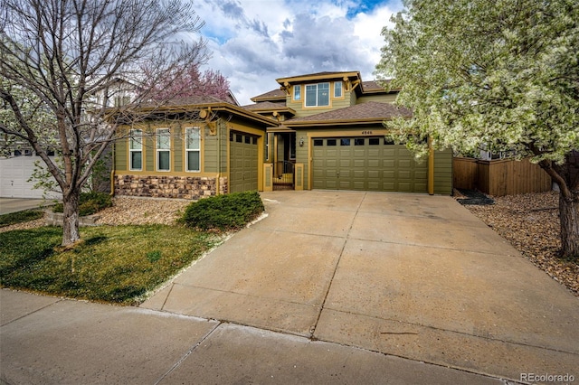 prairie-style home with concrete driveway, stone siding, a shingled roof, an attached garage, and fence