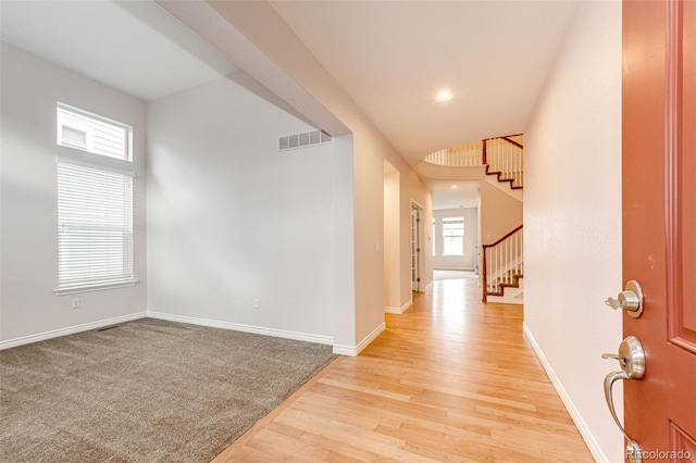 interior space with baseboards, light wood-type flooring, visible vents, and stairs