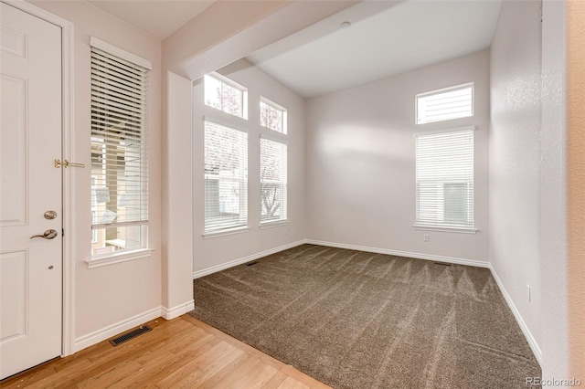 interior space featuring baseboards, carpet flooring, wood finished floors, and visible vents