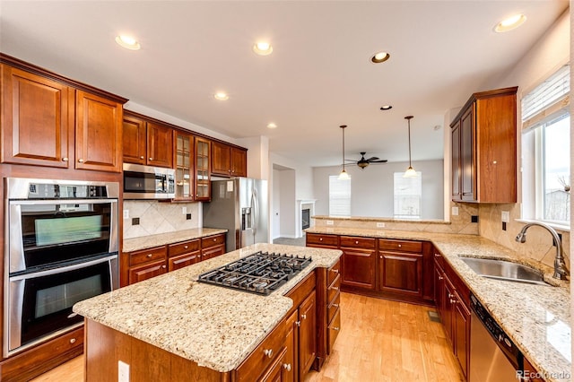 kitchen featuring a sink, recessed lighting, light wood-style floors, light stone counters, and appliances with stainless steel finishes