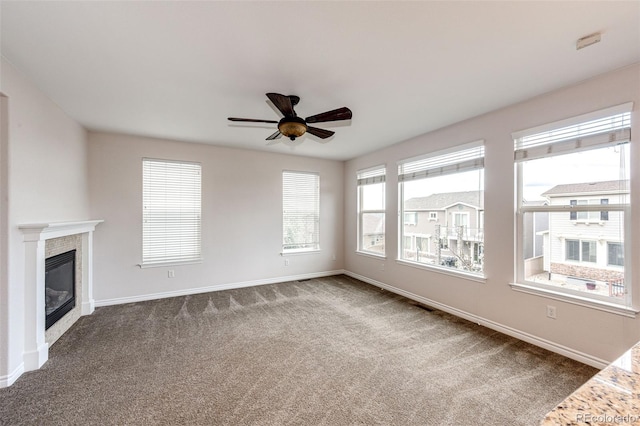 unfurnished living room featuring a fireplace, baseboards, a ceiling fan, and carpet