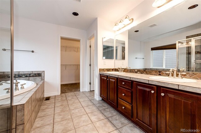 full bathroom with a sink, visible vents, tile patterned flooring, a shower stall, and a walk in closet
