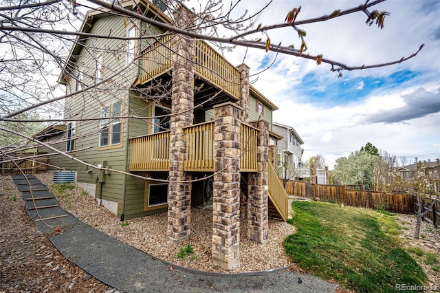 view of side of home with stairway, fence, and a balcony