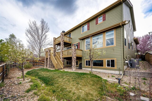 rear view of house featuring a fenced backyard, central air condition unit, a wooden deck, stairs, and a yard