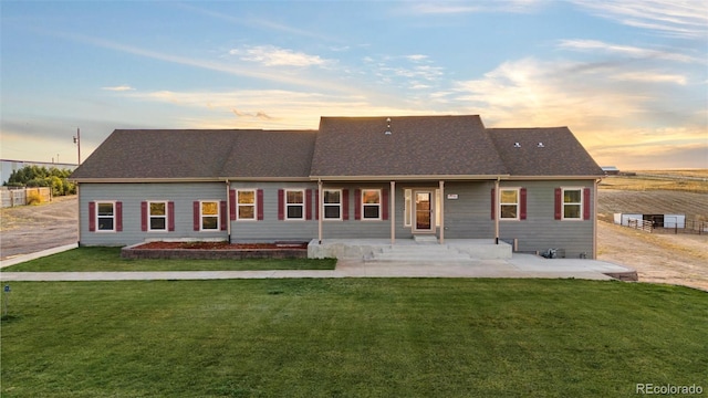 back house at dusk featuring a yard and a patio area