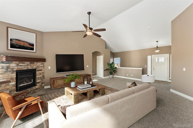 carpeted living room with a stone fireplace, lofted ceiling, and ceiling fan