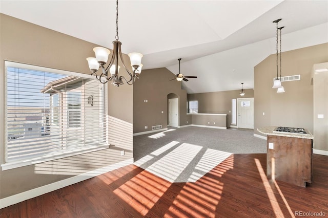 unfurnished dining area with ceiling fan with notable chandelier, vaulted ceiling, and dark hardwood / wood-style floors