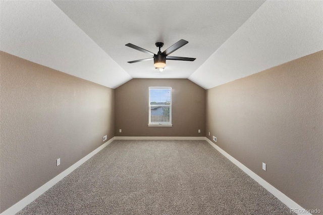 additional living space with a textured ceiling, lofted ceiling, carpet flooring, and ceiling fan