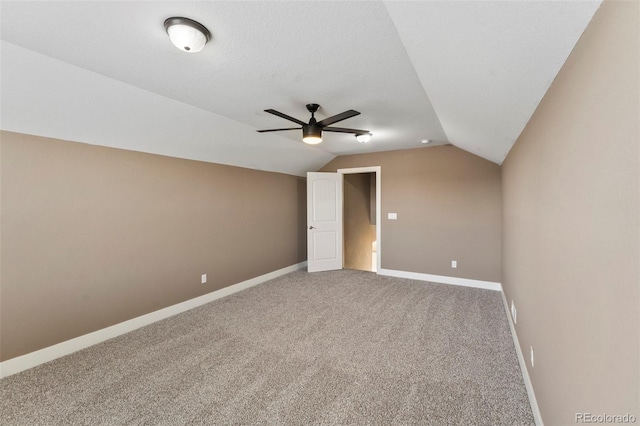 carpeted spare room featuring ceiling fan and vaulted ceiling