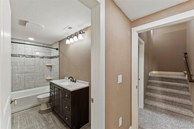 full bathroom featuring tiled shower / bath, vanity, toilet, and a textured ceiling