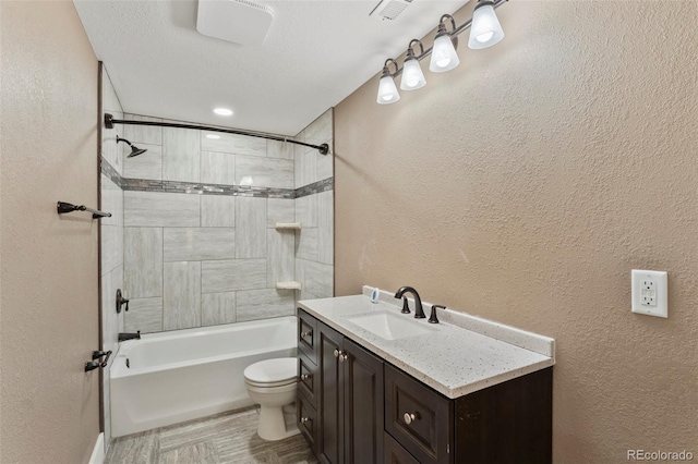 full bathroom featuring vanity, tiled shower / bath combo, toilet, and a textured ceiling