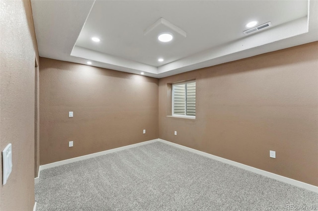 spare room with carpet and a tray ceiling