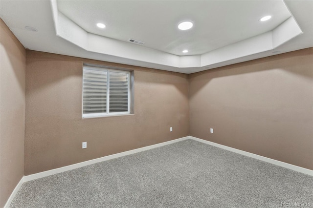 unfurnished room with a raised ceiling and carpet flooring