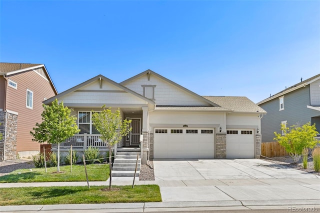 craftsman-style home featuring fence, covered porch, stone siding, an attached garage, and driveway