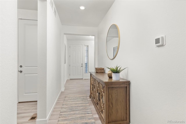hall with baseboards, visible vents, and light wood-type flooring