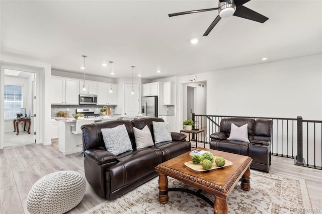 living room with light wood-style floors, a ceiling fan, and recessed lighting