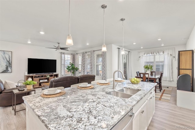 kitchen featuring a sink, light wood finished floors, open floor plan, recessed lighting, and white cabinetry