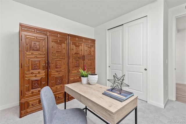 home office with baseboards and light carpet
