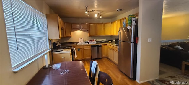 kitchen with stainless steel appliances, light brown cabinetry, and light hardwood / wood-style flooring