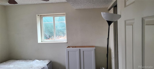 bedroom with ceiling fan and a textured ceiling