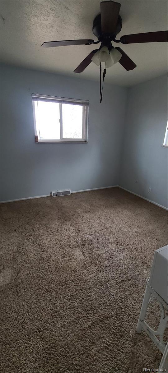 carpeted spare room with ceiling fan and a textured ceiling