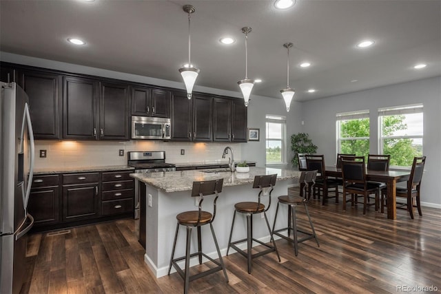 4025 Trail Stone Cir, Castle Rock, CO 80108 - kitchen with stainless steel appliances, dark wood-style flooring, recessed lighting, decorative backsplash, and light stone countertops