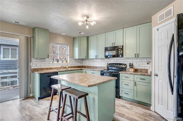 kitchen featuring a breakfast bar area, decorative backsplash, a kitchen island, and black appliances