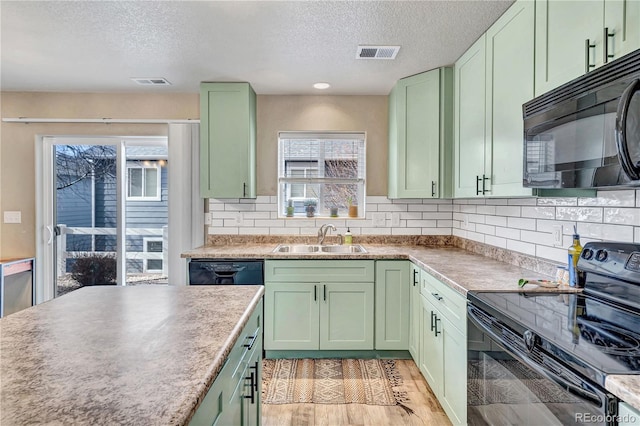 kitchen with green cabinets, sink, black appliances, and a textured ceiling