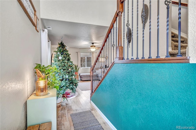 stairway with ceiling fan, a textured ceiling, and hardwood / wood-style flooring