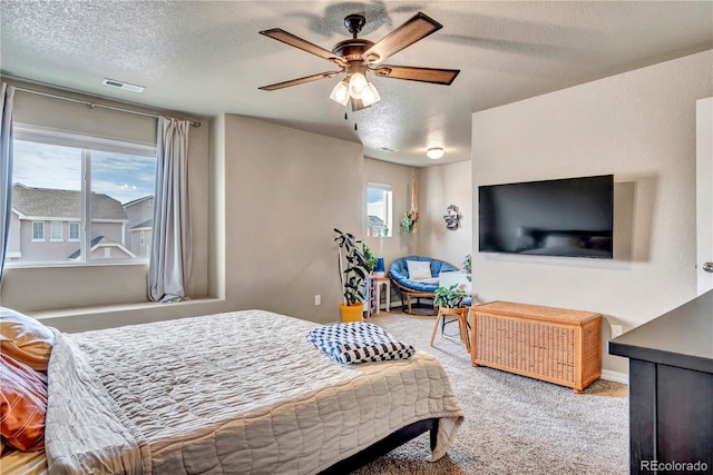 bedroom with ceiling fan, carpet floors, and a textured ceiling