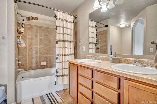 bathroom featuring vanity, a textured ceiling, tile patterned floors, and shower / bath combo with shower curtain