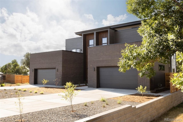 contemporary home with brick siding, driveway, and fence