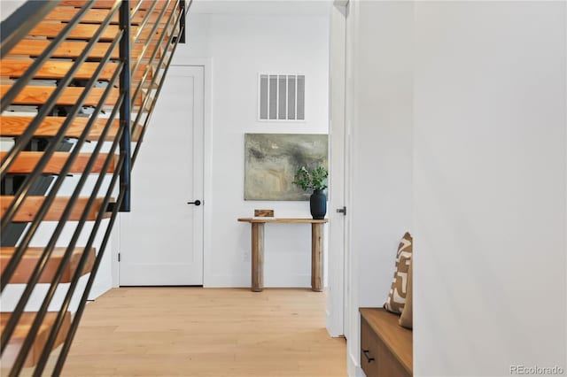 corridor with visible vents, stairs, and light wood-type flooring