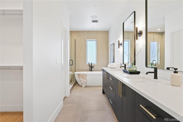 full bathroom with visible vents, a freestanding bath, double vanity, tile patterned floors, and a sink