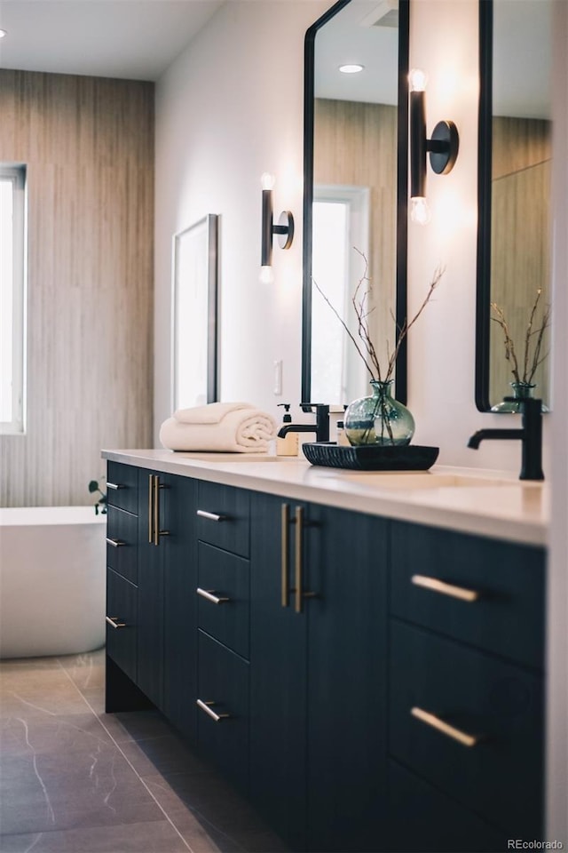 bathroom with a sink, double vanity, marble finish floor, and a freestanding bath