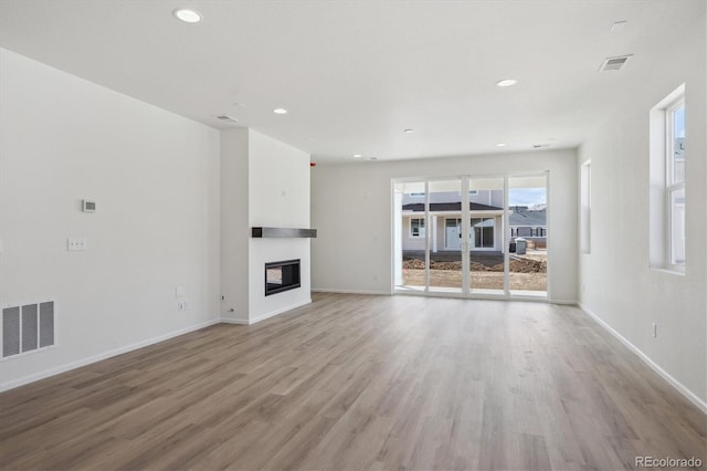1306 Sienna Peak Cir, Erie, CO 80516 - unfurnished living room featuring baseboards, visible vents, light wood-style floors, and a glass covered fireplace