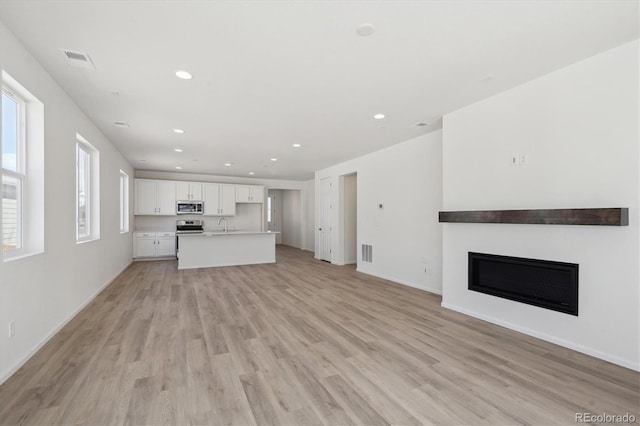 1306 Sienna Peak Cir, Erie, CO 80516 - unfurnished living room with visible vents, recessed lighting, light wood-type flooring, and a glass covered fireplace