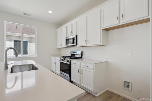1306 Sienna Peak Cir, Erie, CO 80516 - kitchen with white cabinetry, visible vents, a sink, and stainless steel appliances
